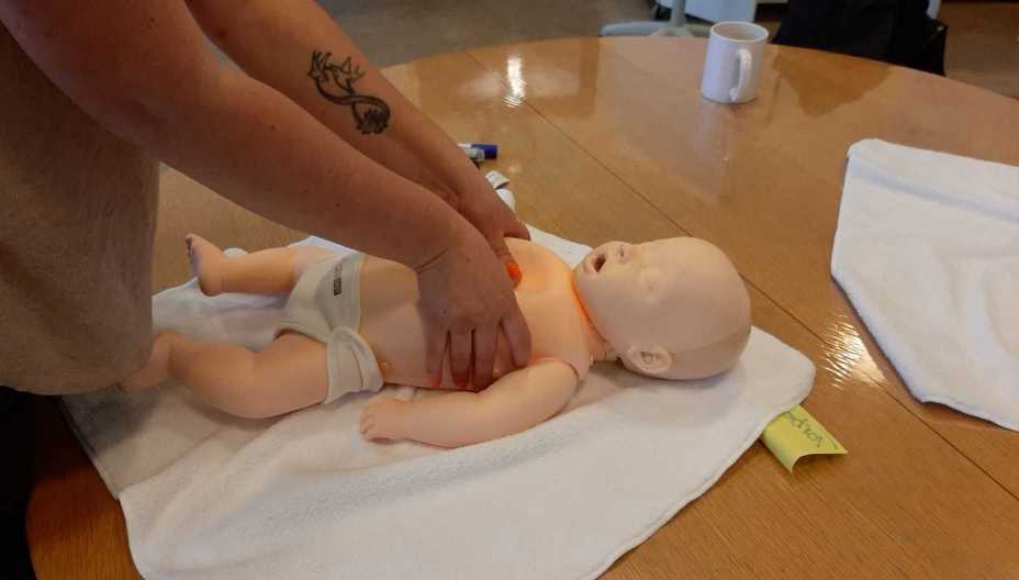 person laver førstehjælp på en dukke af en baby